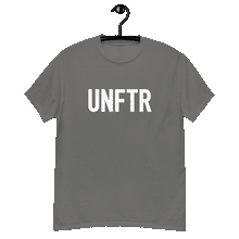 Load image into Gallery viewer, Charcoal gray colored classic tee shirt that says UNFTR in white on the front and Meeting People Where They Are in white on the back