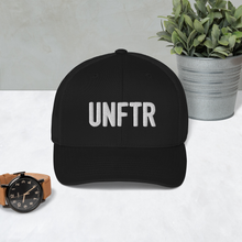 Load image into Gallery viewer, Black trucker hat with black side panels with white UNFTR logo embroidered on the front