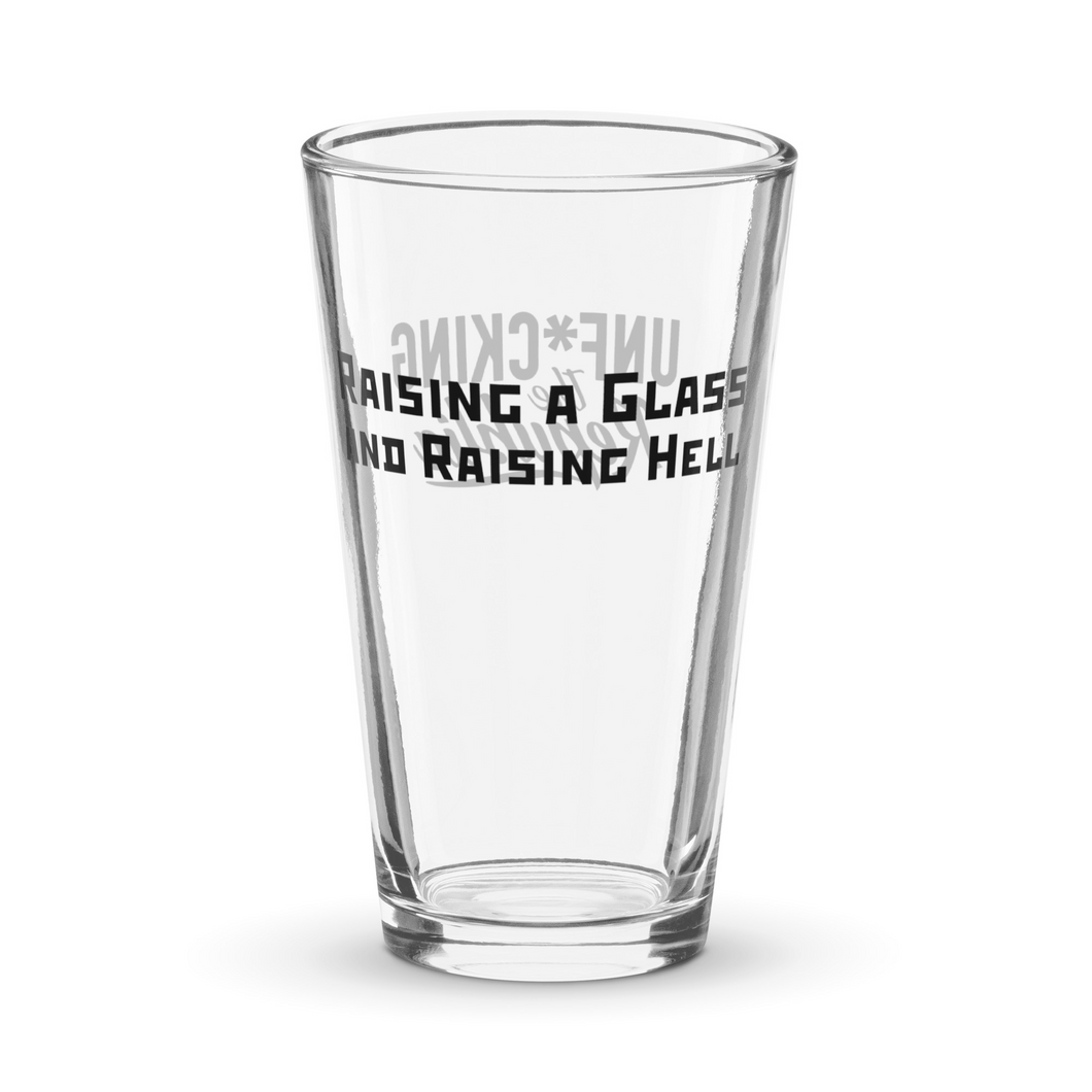 Text that reads Raising a glass and raising hell and the Unf*cking The Republic logo printed in black on a pint glass.