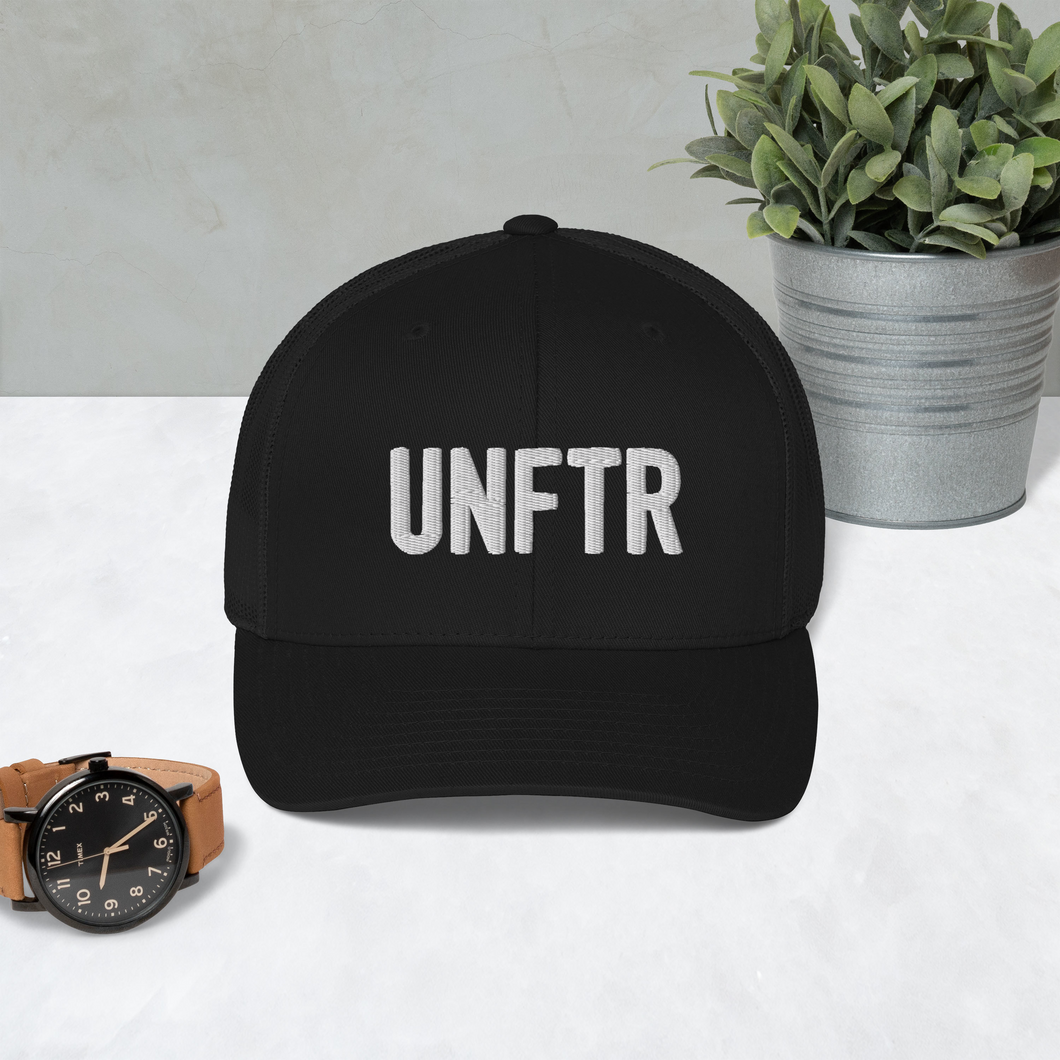 Black trucker hat with black side panels with white UNFTR logo embroidered on the front