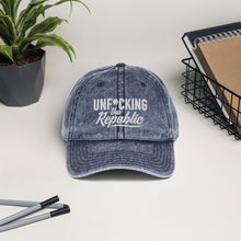 Load image into Gallery viewer, Blue denim-like vintage wash dad cap with white Unf*cking The Republic logo embroidered on the front.
